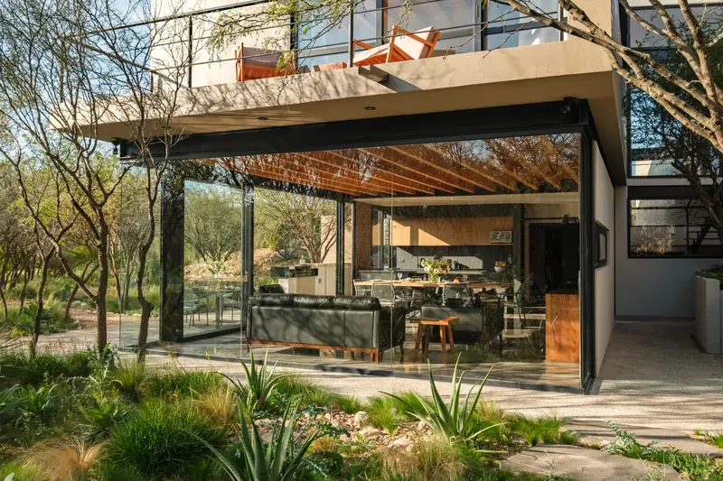 Casa contemporánea con sala abierta al jardín bajo pérgola
